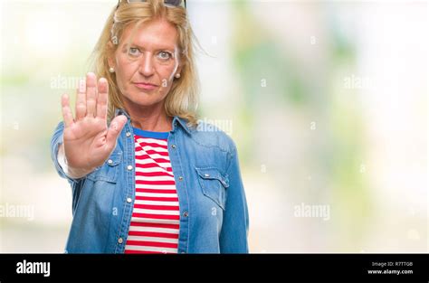 Blonde Frau mittleren Alters über isolierte Hintergrund tun halt Singen mit der Hand Warnung
