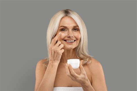 Premium Photo Skincare Routine Beautiful Mature Lady Applying Moisturizing Cream On Face
