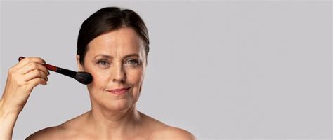 Femme mature à l aide de pinceau de maquillage sur son visage avec copie espace Photo Gratuite