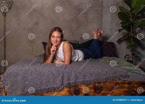 Smiling Woman Lying On Her Stomach In Bed Stock Image Image Of Jeans