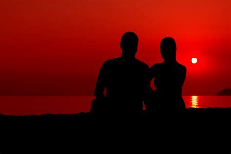 Couple Sitting On The Beach And Watch The Sunset Stock Photo Download