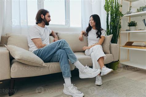 Man And Woman Friends Sitting On The Couch And Smiling Merrily Talking