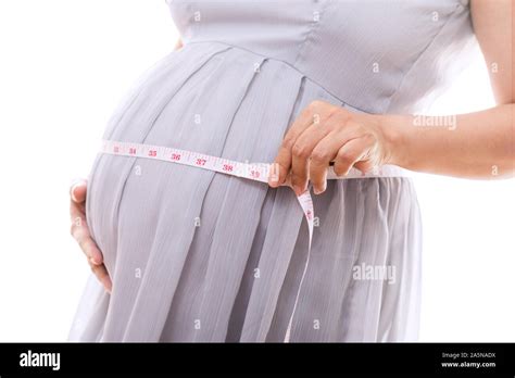 Pregnant Woman Measuring Her Belly With Tape While Standing Over White