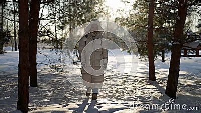 Happy Man In White Down Jacket Is Walking In Snowy Park In Winter Between Naked Trees Stock