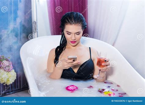 Brunette Woman Is Sitting In Bath And Chatting On Smartphone Stock Photo Image Of