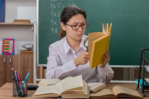 Молодая женщина-учитель в очках с книгами выглядит смущенной и ...
