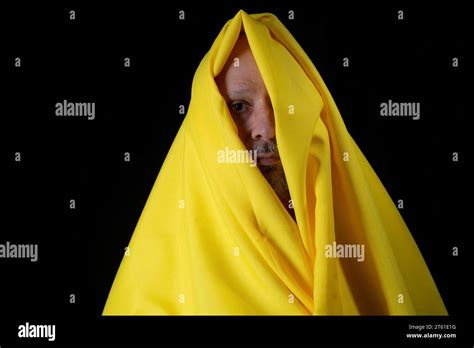 Bald Bearded Man With A Yellow Cloth Over His Head Against Black