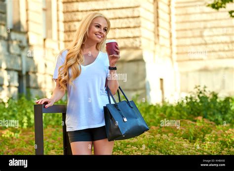 Une belle jeune femme blonde debout dans l ombre en face d un bâtiment ancien et d avoir un café
