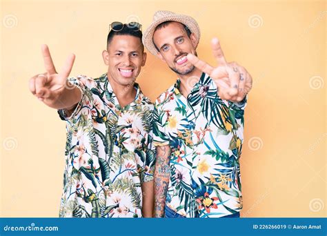 Joven Pareja Gay De Dos Hombres Con Sombrero De Verano Y Camisa Hawaiana Sonriendo Con La Lengua