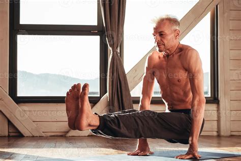 Man With A Naked Torso Practicing Yoga Training In Studio In Front Of A Window Copy Empty