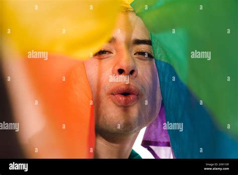 Close Up Front View Of Latin Gay Man Looking At Camera Blowing A Kiss Covered By A Pride Flag
