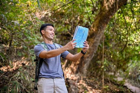 Active Asian Male Traveler Looking Trail Direction On The Map Enjoys