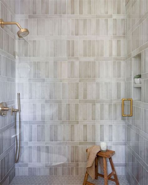 A White Tiled Bathroom With A Stool And Shower