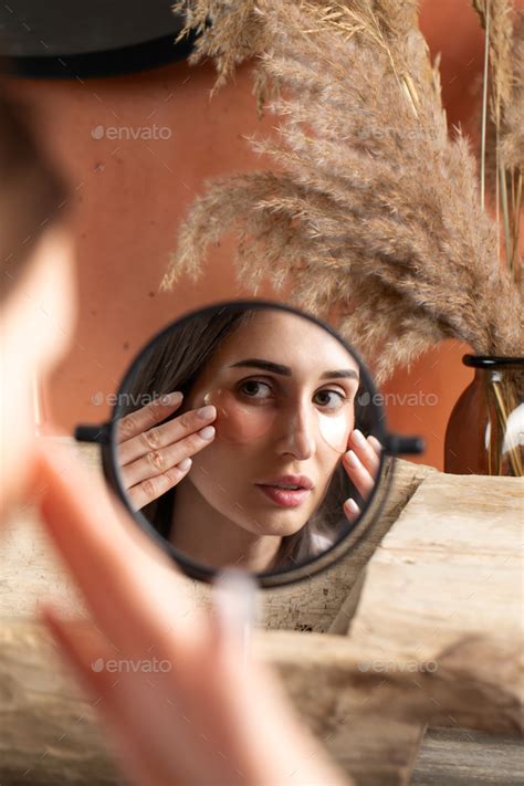 Mirror Reflection Of Woman Applying Under Eye Patch At Dressing Table