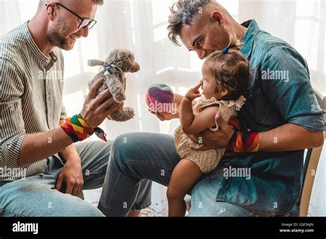 Un couple gay masculin avec une fille adoptive à la maison deux beaux pères jouant avec leur