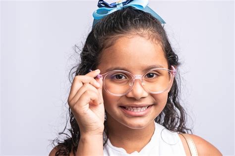 Retrato de una chica latina sonriente con gafas mirando a la cámara sobre un fondo blanco