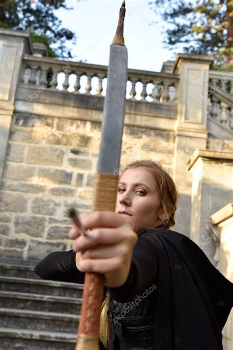 Portrait Of Beautiful Female Model With Blonde Plait Wearing Black Leather Catsuit And Hooded