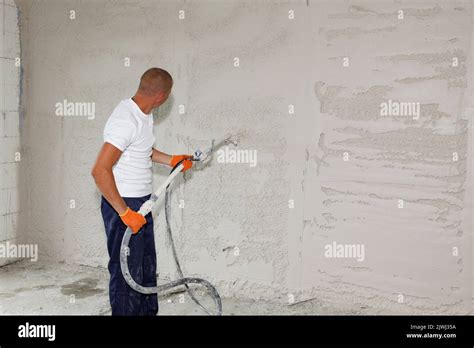 A Man Is Applying Stucco On The Wall Plastering Coating The Wall By