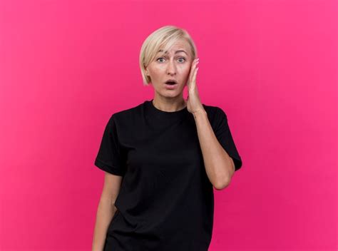 Überraschte blonde slawische Frau mittleren Alters Kopf berührt