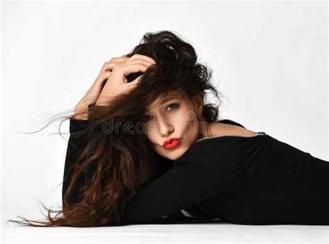 Playful Sensual Woman Brunette With Long Curly Hair In Black Dress Is Lying Posing On The Floor