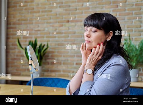 Mature Woman Admiring Her Face In Mirror Touching Skin With Hands Stock Photo Alamy