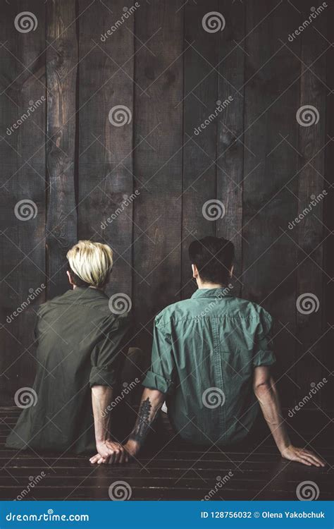 Pares Gay Jovenes Que Se Sientan En El Piso Delante De La Pared De