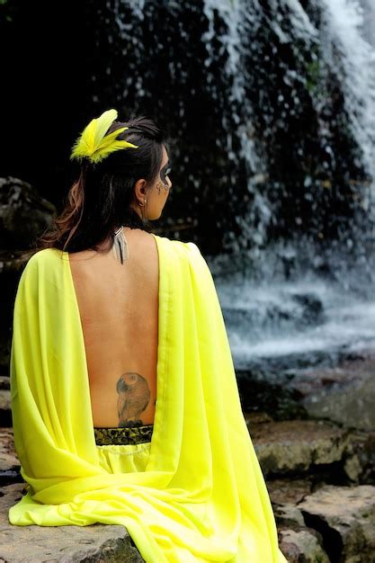 Premium Photo Rear View Of Woman Sitting On Rock Against Waterfall