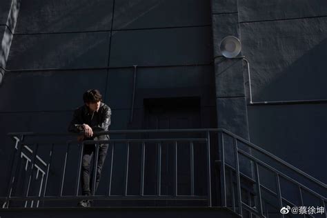 A Man Standing On Top Of A Metal Hand Rail Next To A Black Building And