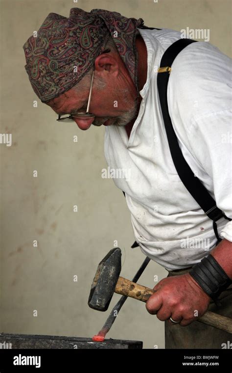 A Blacksmith Pounding Red Hot Iron To Create A Tool Stock Photo Alamy