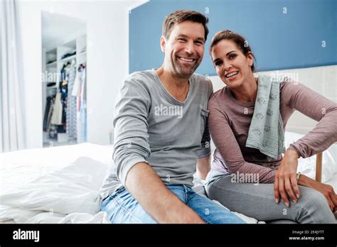 Happy Mature Couple Sitting On Bed In Bedroom Stock Photo Alamy
