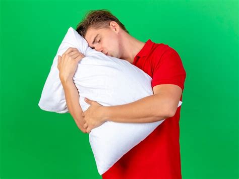 Jeune bel homme malade blonde étreignant et embrassant l oreiller avec les yeux fermés isolé sur