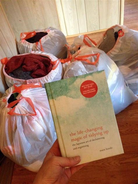 A Person Holding Up A Book In Front Of Some Bags Filled With Clothes