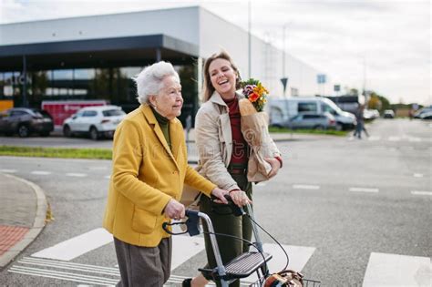 Mature Granddaughter Helping Grandmother Load Groceries In To The Car Senior Woman Shopping At