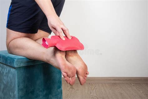 A Man Holds A Heating Pad With Hot Water Near The Soles Of His Feet Pain Relief And Treatment
