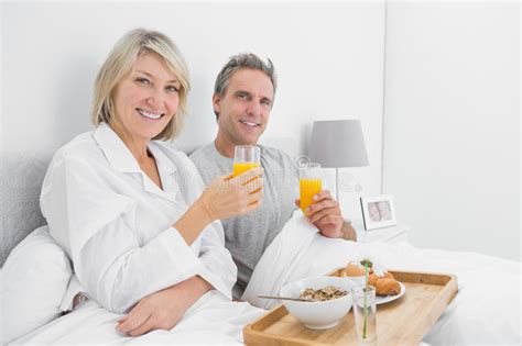 Pares Felices Que Comen Zumo De Naranja En El Desayuno En Cama Foto De