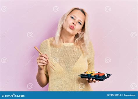 Belle Caucasienne Blonde Femme Mangeant Des Sushi à L aide De Baguettes Regardant La Caméra
