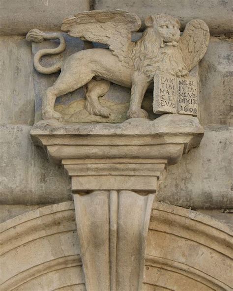 A Lion Statue On The Side Of A Building Next To A Doorway With An Arch