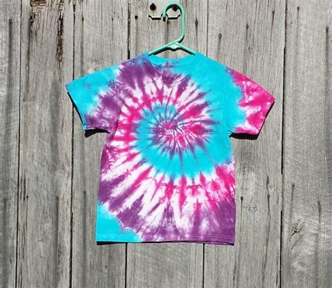 A Tie Dyed Shirt Hanging On A Wooden Fence