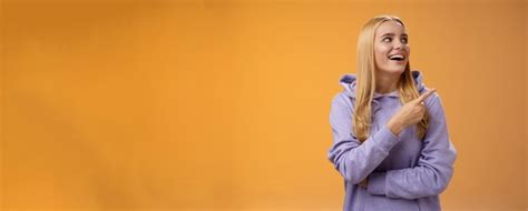 Amusée insouciante joyeuse blonde européenne en capuchon pointant vers la droite heureuse