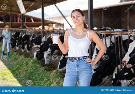 женщины-молочницы позируют со стаканом молока на молочной ферме ...