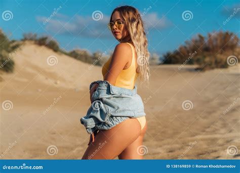 Portrait Of A Blonde Girl In A Yellow Swimsuit Showing Her Body Beautiful Model In Sunglasses