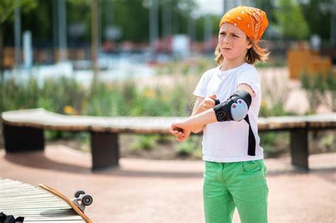 Preadolescent Boy Putting On The Protective Gear Before Skateboarding