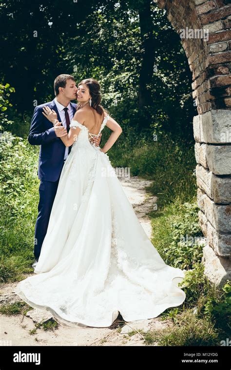 Full Length Wedding Portrait Of The Groom Tenderly Kissing His Lovely