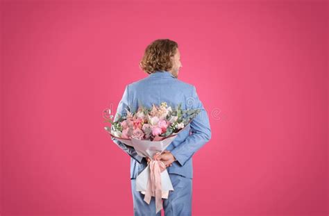 Man In Stylish Suit Hiding Beautiful Flower Bouquet Behind His Back