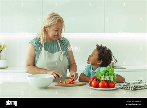 Cute Mature Woman And Her Son Preparing Healthy Food Together Standing At A Worktop In The