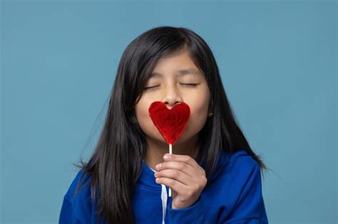 Chica latina mexicana besando un concepto de amor propio piruleta en forma de corazón Foto Premium