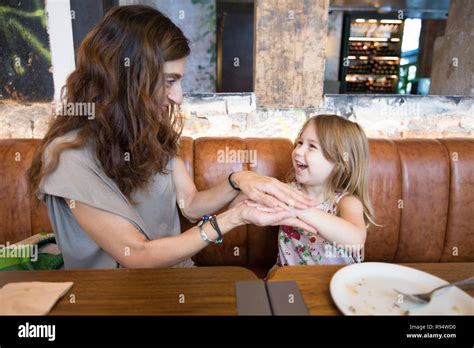 Four Years Age Blonde Girl Happy Playing With Hands And Laughing With Woman Mother Sitting In
