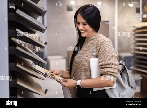 Happy Brunette Female Interior Designer Choosing Flooring Tile Color Texture Samples At Store