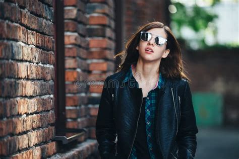 Πορτρέτο μόδας τρόπου ζωής του κοριτσιού Brunette στο μαύρο ύφος βράχου