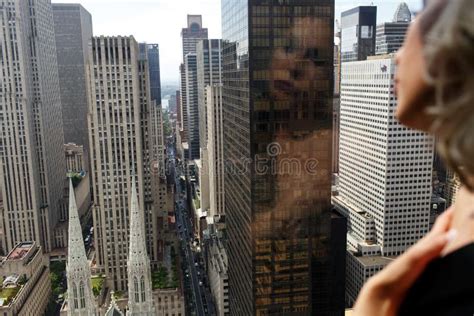 Woman In Black Silk Robe Stands With Naked Shoulders Before A Panoramic Window In New York Stock